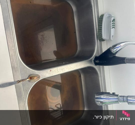 כיור כפול עם מים מלוכלכים וברז מטבח